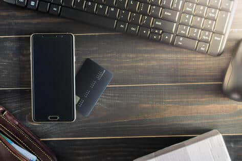 Movil y tarjeta de crédito al lado de un teclado de ordenador